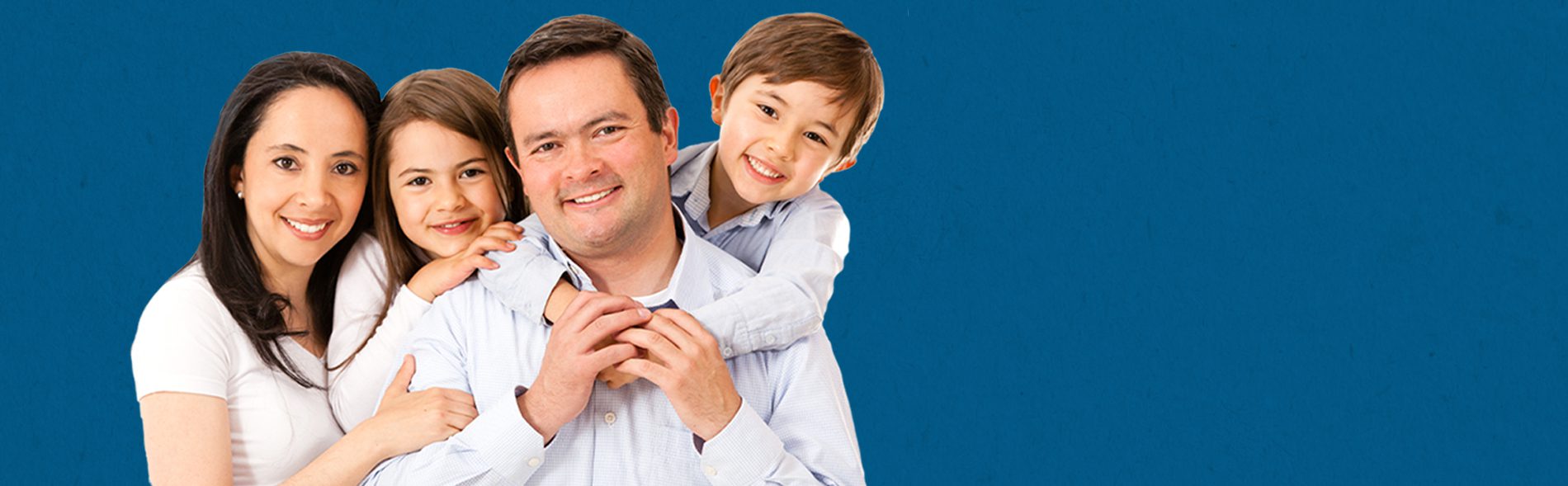 A family of four smiling at the camera in front of a solid blue background.