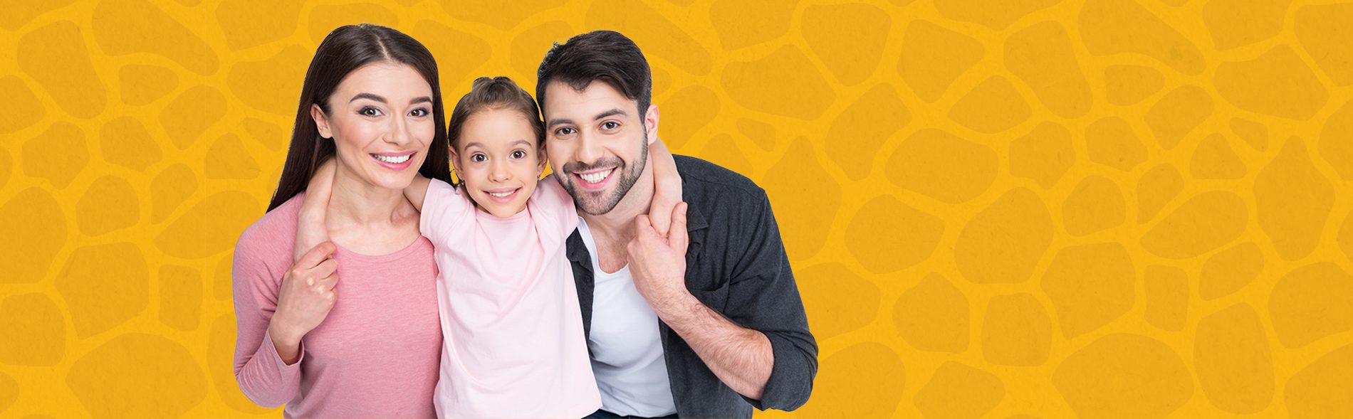A family of three smiling at the camera in front of a yellow patterned background.