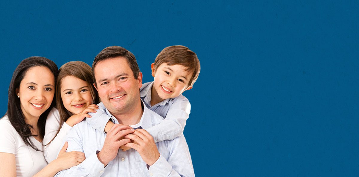 A family of four smiling at the camera in front of a solid blue background.